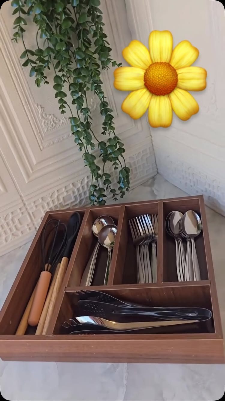 Wooden cutlery tray holding various metal spoons, forks, and wooden kitchen utensils.