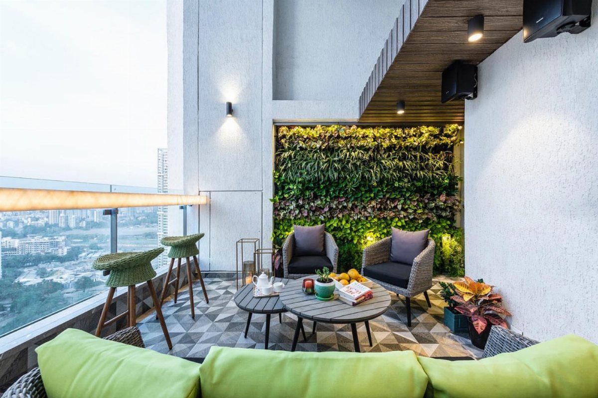 Modern balcony lounge with wicker armchairs, a wooden coffee table, and a lush vertical garden wall.