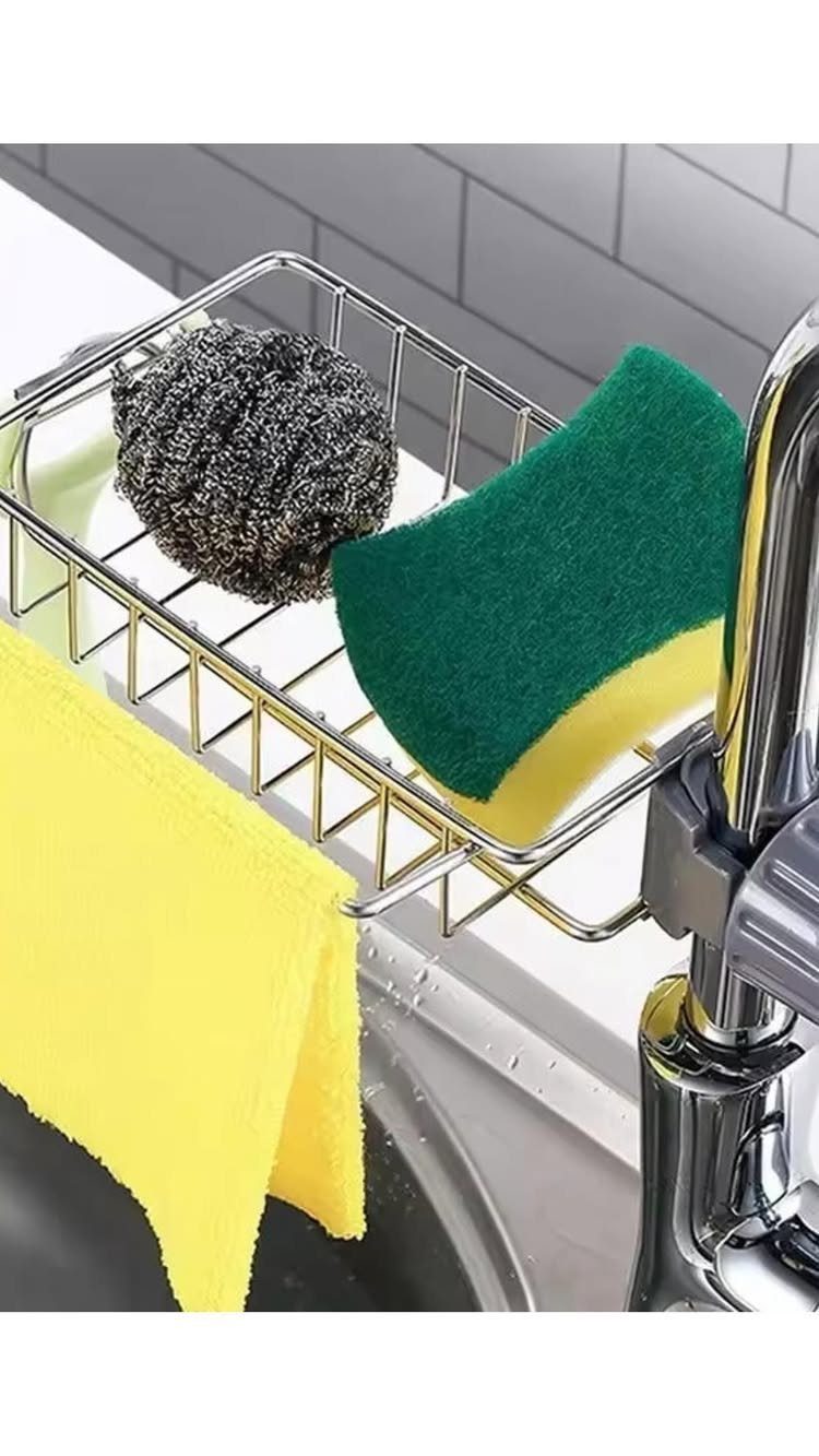 A silver wire sink caddy holding a green sponge and a steel scouring pad near a faucet.