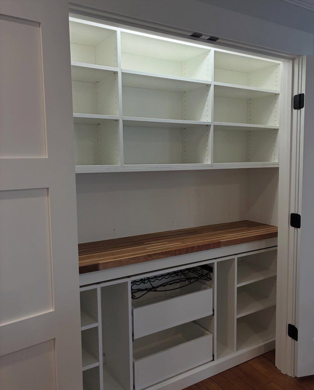 White built-in pantry closet with wooden countertop and open shelving units.