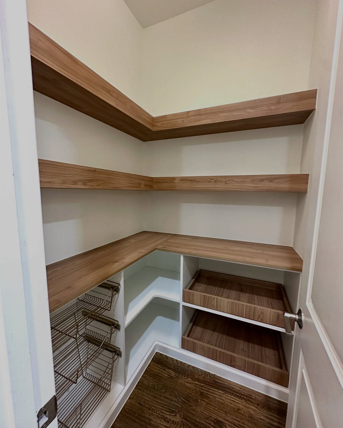 Thick light-brown wood shelves installed in a corner pantry with white built-in compartments below.