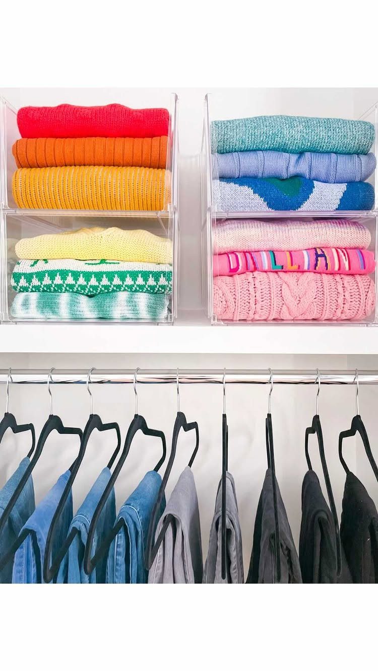 Closet Organization: 8 Sweater Storage Ideas That Save Space 7 Folded colorful sweaters organized in clear acrylic bins on a white shelf above hanging clothes.