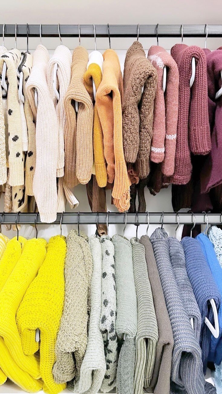 Closet Organization: 8 Sweater Storage Ideas That Save Space 5 Knitted sweaters in various colors hanging on hangers in a closet organization setup.