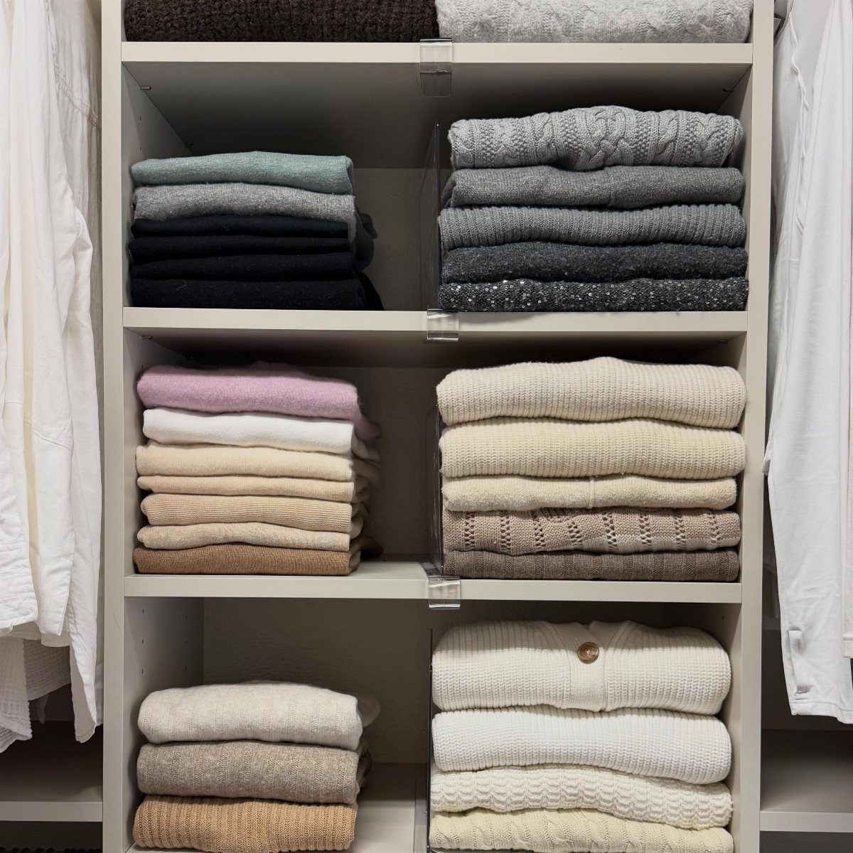 Closet Organization: 8 Sweater Storage Ideas That Save Space 3 Folded sweaters in neutral colors stacked neatly on white open closet shelves.