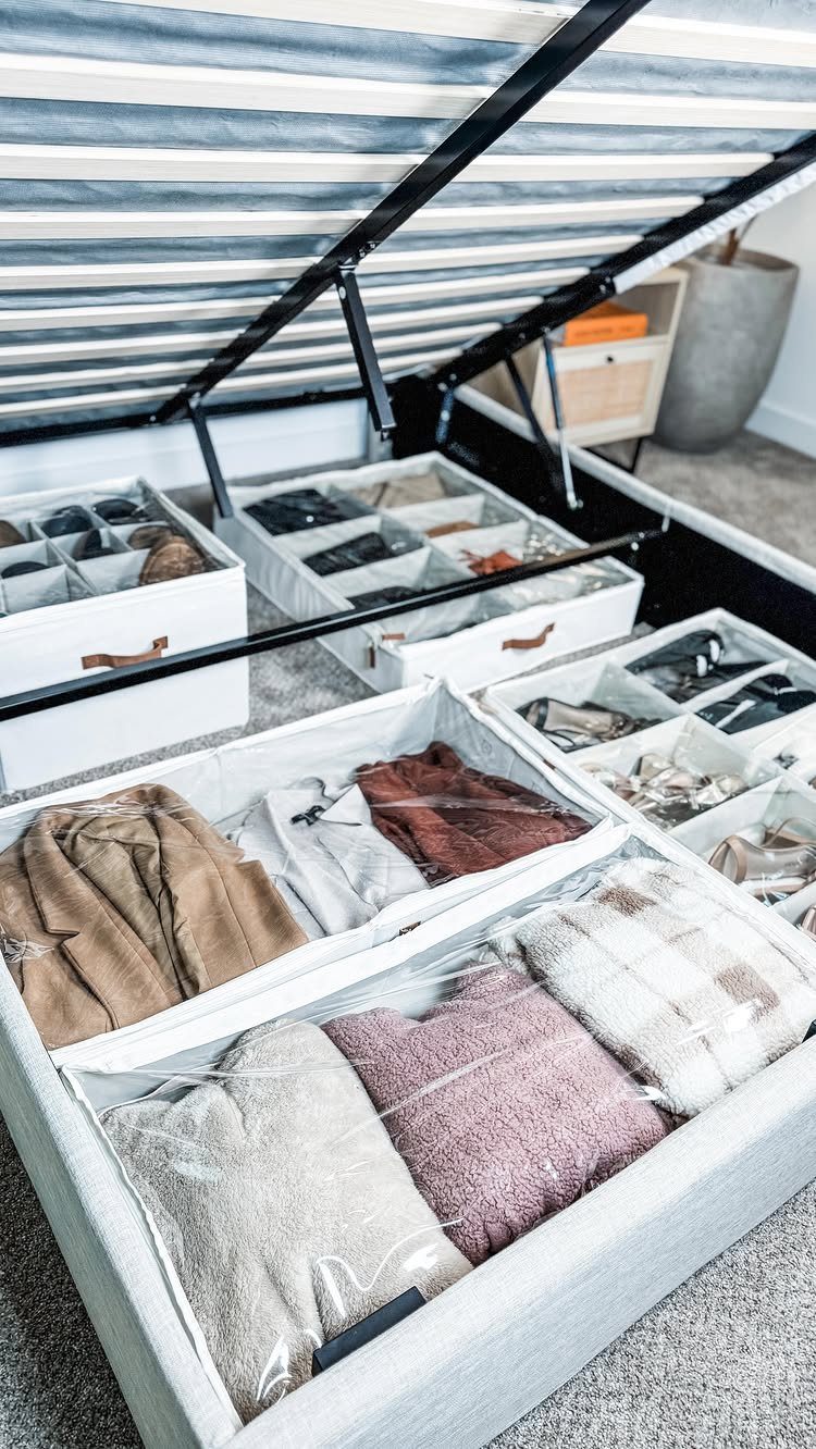 Closet Organization: 8 Sweater Storage Ideas That Save Space 1 White fabric storage bins filled with folded sweaters organized on a grey carpeted floor.