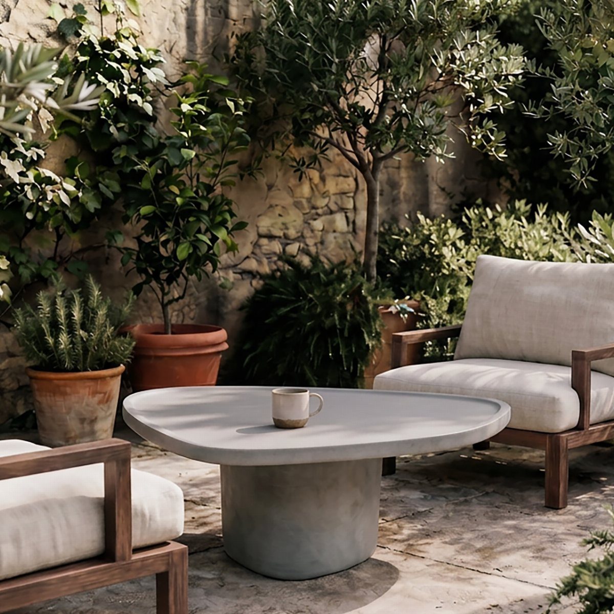A round grey concrete coffee table centered in a lush outdoor patio setting.