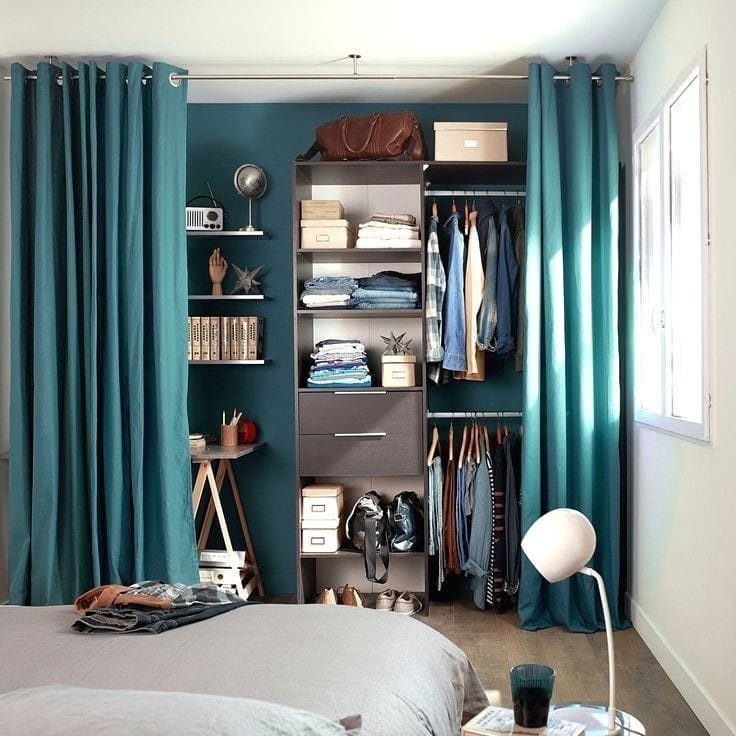 11 Curtain Closet Ideas for Style and Space 7 Teal curtains frame an open closet with organized shelves and hanging clothes against a teal wall.
