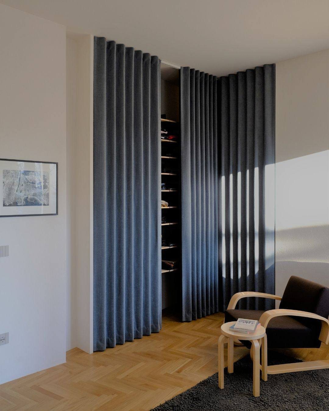 11 Curtain Closet Ideas for Style and Space 4 Dark grey pleated fabric panels hanging from the ceiling to cover a closet opening.