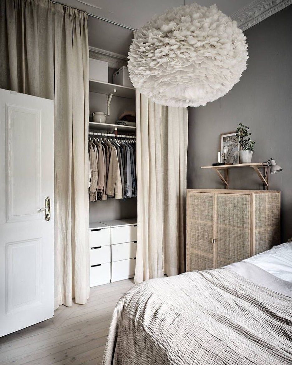 11 Curtain Closet Ideas for Style and Space 6 Beige linen curtains covering an open closet with clothes and white storage drawers.
