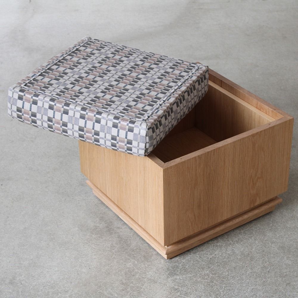 A wooden storage ottoman with a patterned lid partially opened to show the empty interior.