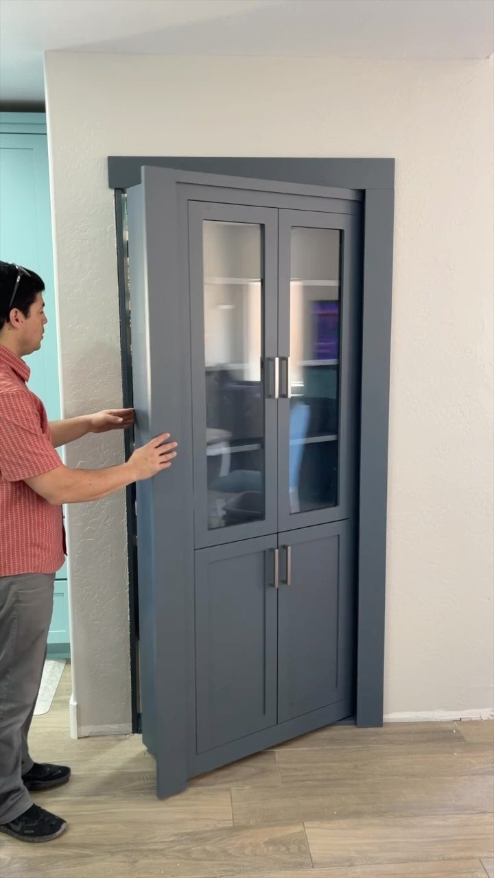 A man pushes a large grey bookcase that serves as a hidden Murphy door.