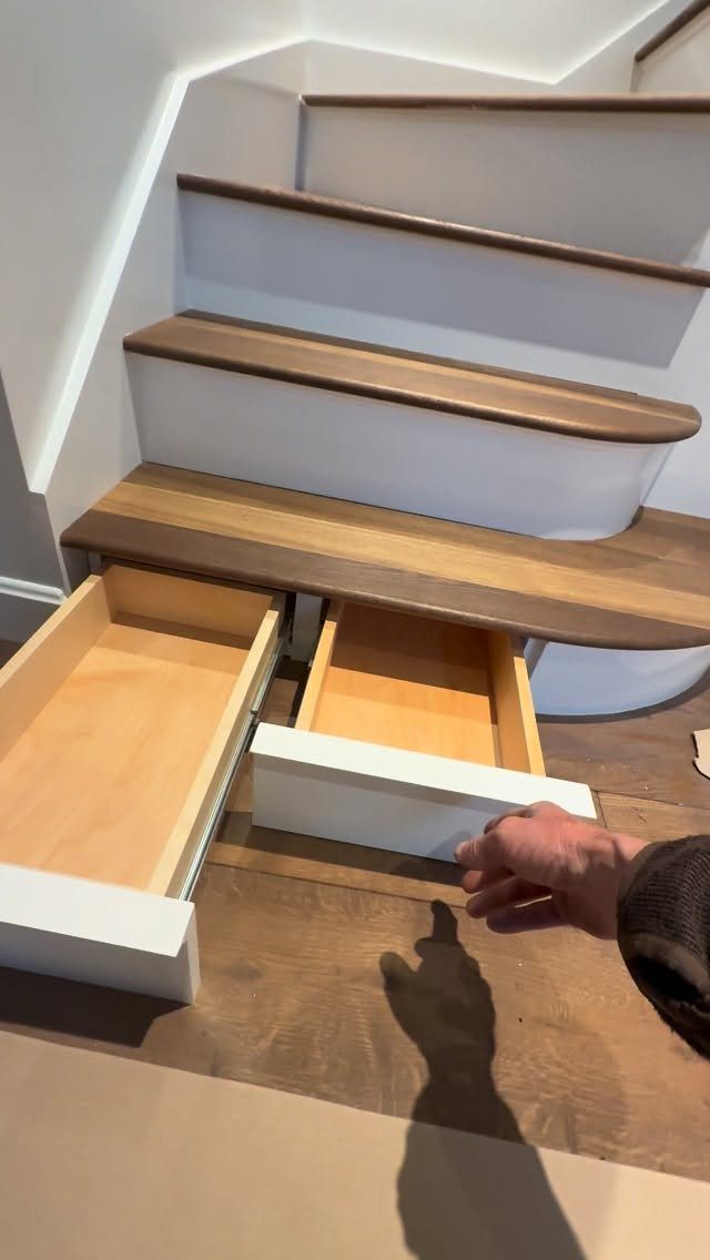Two white drawers pulled out from the bottom steps of a wooden staircase.