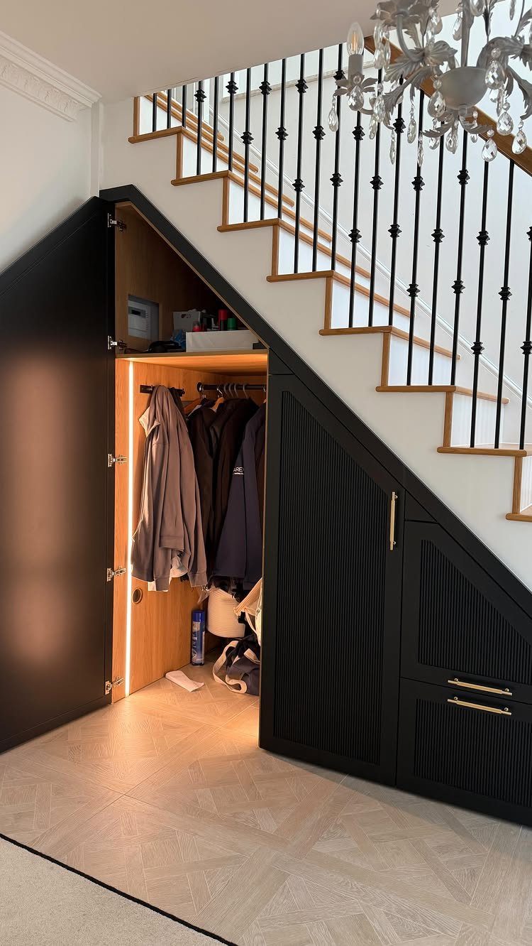 Black built-in storage unit under a staircase featuring an open closet and textured drawers.
