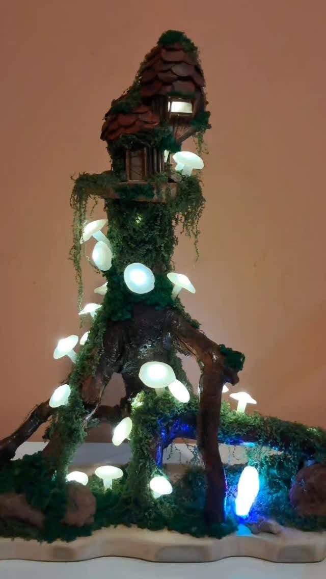 23 Fairy Garden Ideas for Tiny Houses, Teacups and Tree Trunks 9 Glowing white mushroom lights scattered across a mossy miniature treehouse structure.