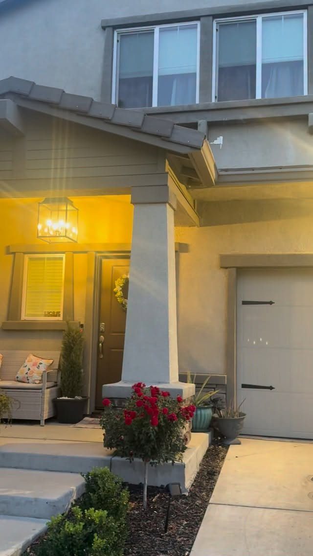 14 Front Porch Decorating Ideas for Every Season 2 A lit front porch featuring a hanging lantern, potted plants, and a small seating area.