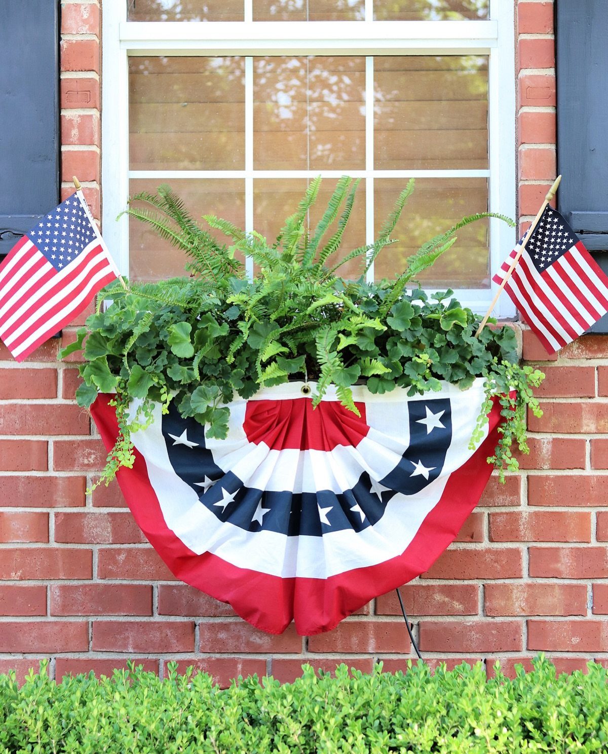 14 Front Porch Decorating Ideas for Every Season 14 Patriotic red, white, and blue bunting with green ferns and small American flags on a brick wall.