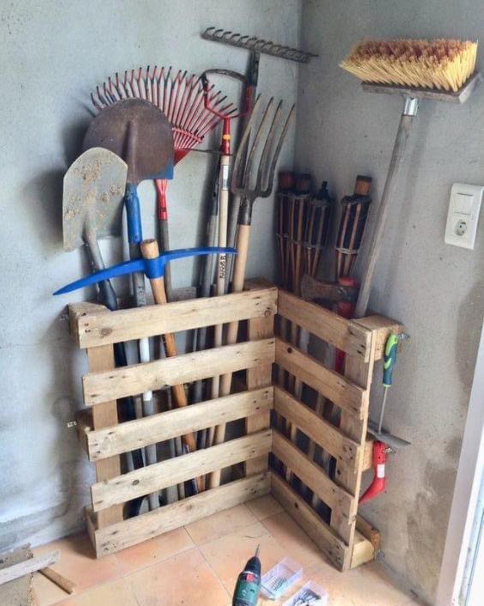 Garage Storage Using Pallets: 5 Projects for Vertical Racks and Tool Cubbies 1 Wooden pallets used as vertical storage racks for garden tools in a corner.
