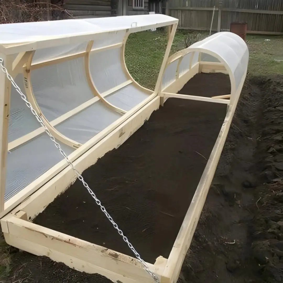 A long wooden raised garden bed with a translucent arched plastic cover filled with dark soil.