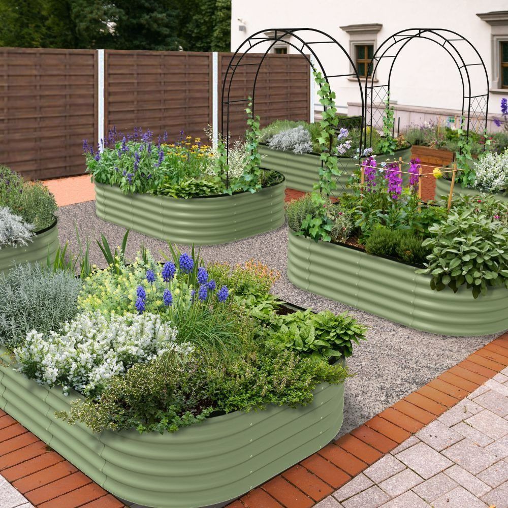 Light green corrugated metal raised garden beds filled with colorful flowers and lush greenery on gravel.