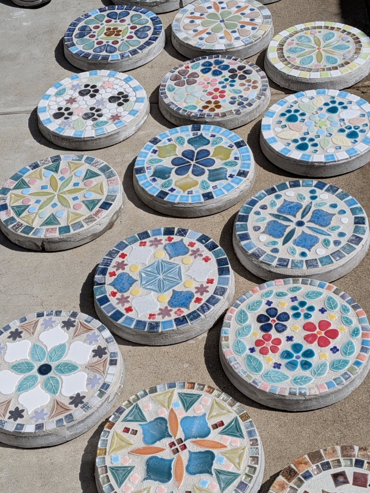 Circular concrete stepping stones with colorful mosaic tile patterns arranged on the ground.