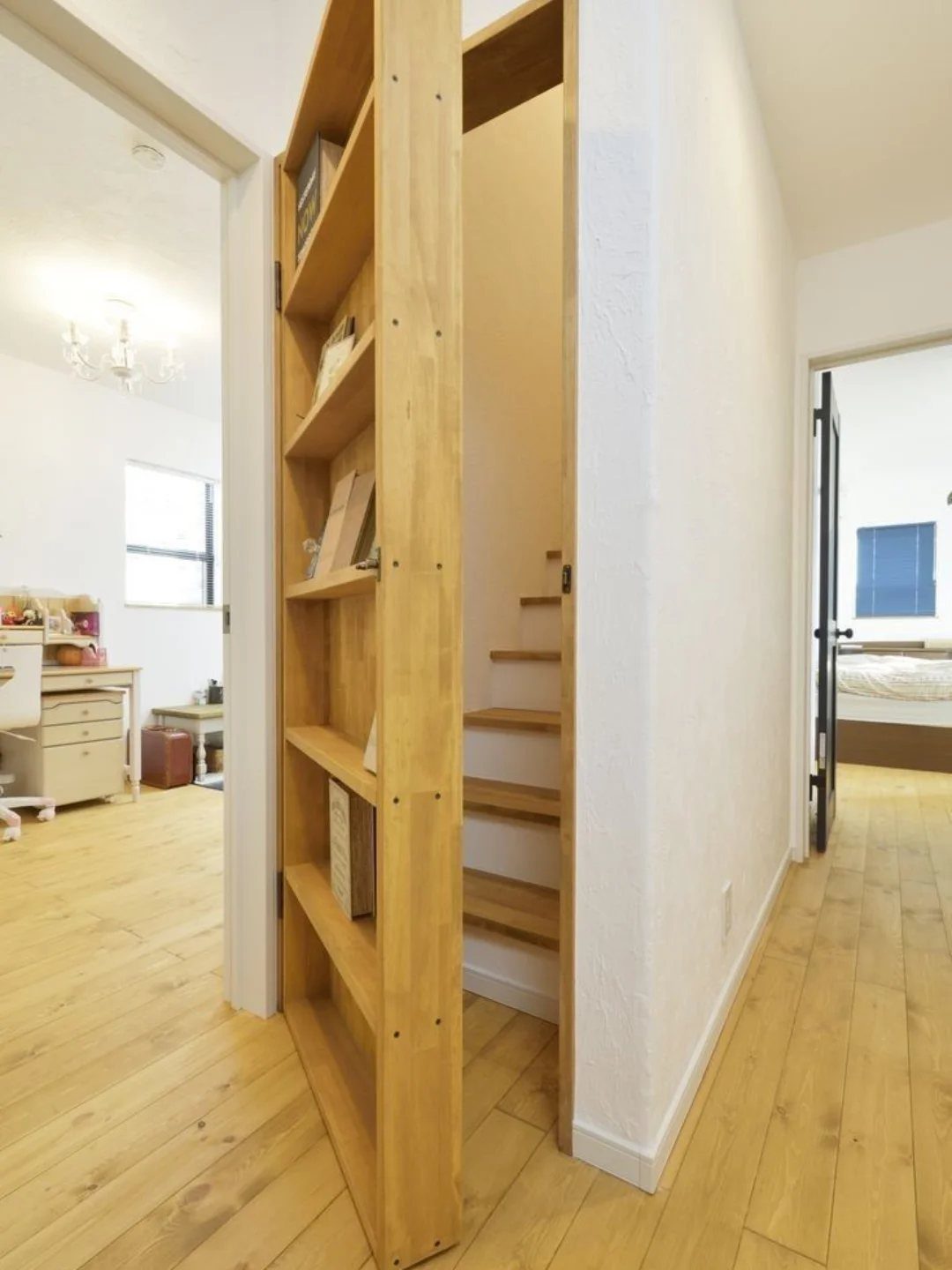 9 Hidden Storage Entrance Ideas for Bookshelf Doors and Hidden Hatches 1 A wooden bookcase door swings open to reveal a hidden staircase in a bright hallway.