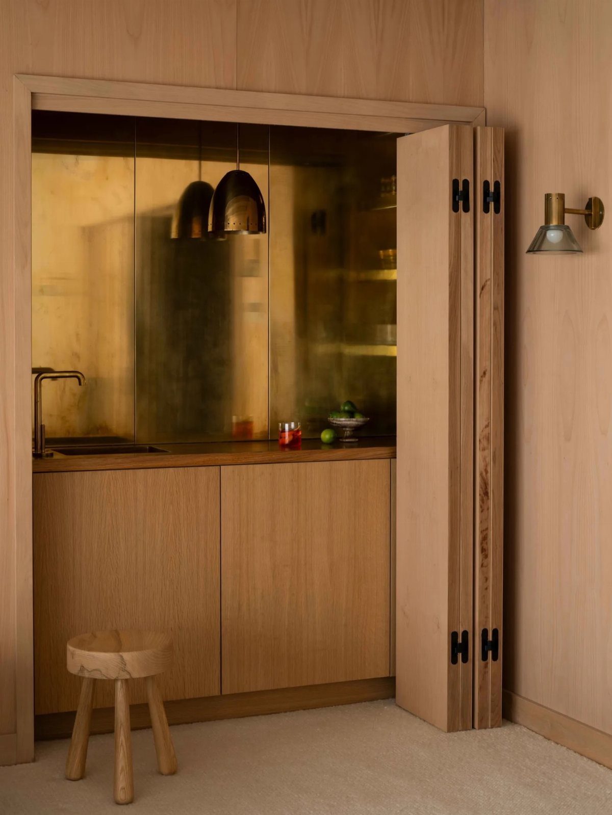9 Hidden Storage Entrance Ideas for Bookshelf Doors and Hidden Hatches 9 Open wooden bifold doors revealing a hidden kitchen area with golden metallic walls and wooden cabinetry.