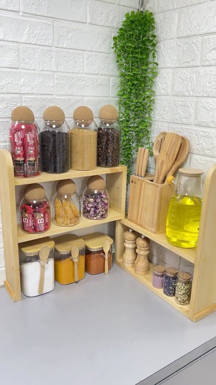 Wooden spice racks filled with glass jars of colorful spices and oils on a grey countertop.