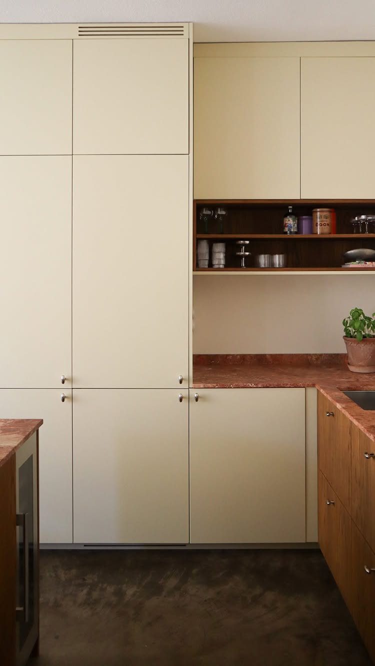 Cream kitchen cabinets paired with a dark wood open shelf containing small jars and containers.