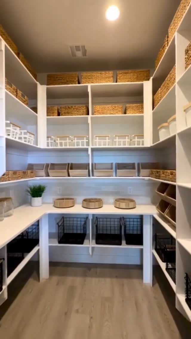 White built-in pantry shelving filled with wicker baskets and organized storage containers.