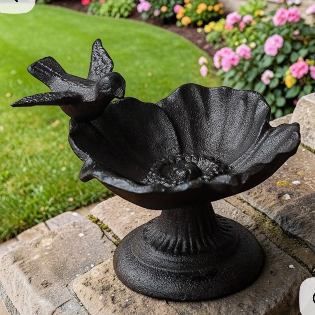 Metal Yard Art Ideas for Your Garden in 7 Styles 5 Black metal flower-shaped bird bath with a small bird sculpture on a stone ledge.