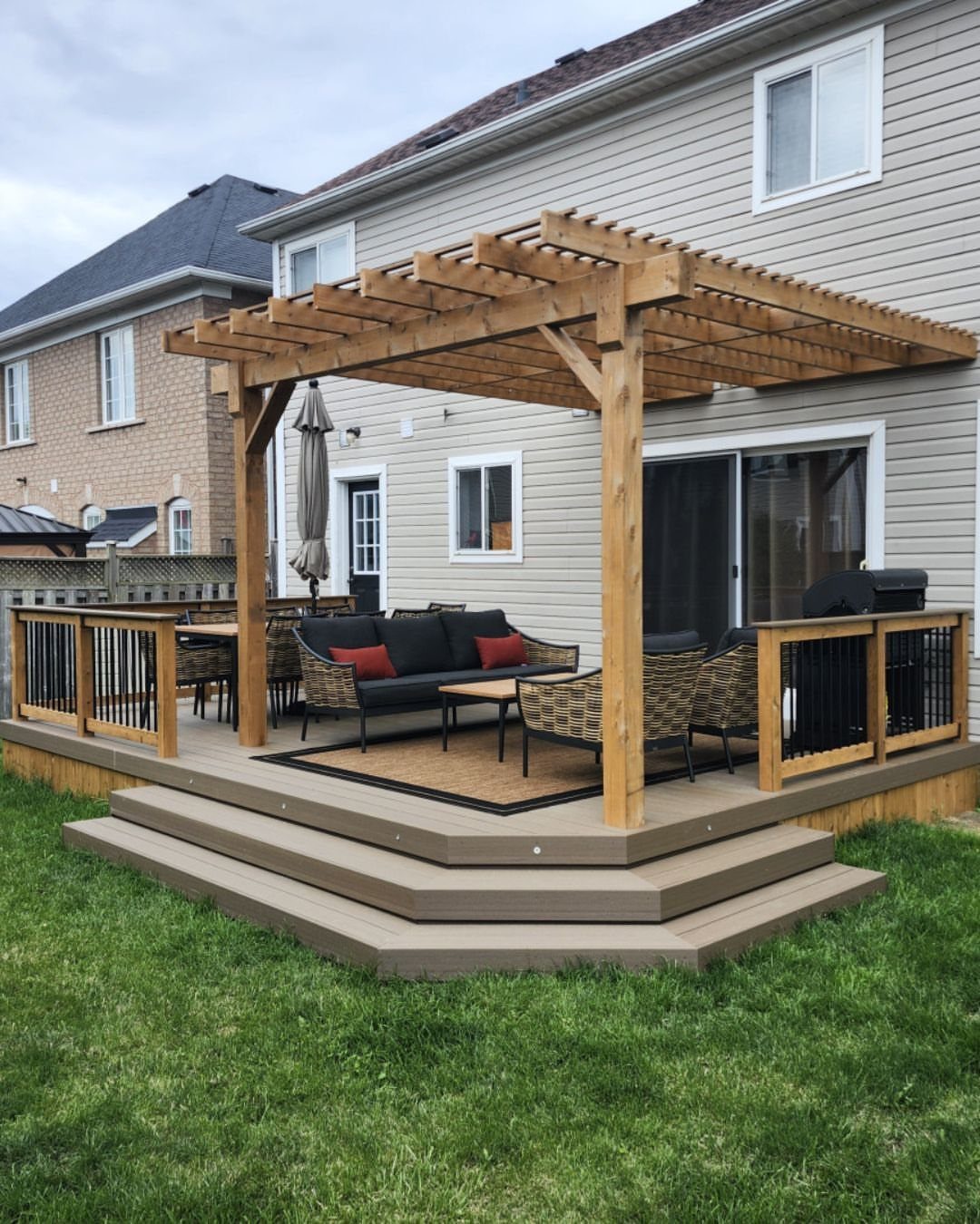 9 Modern Deck with Pergola Ideas for Living, Shade & Dining 9 A large wooden pergola covering a modern outdoor lounge area on a multi-level deck.