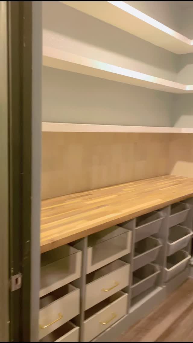 11 No Closet Room Ideas for Clothing Racks, Under-Bed Storage and More 10 Built-in storage unit with wooden countertops, grey drawers, and white floating shelves against a blue wall.