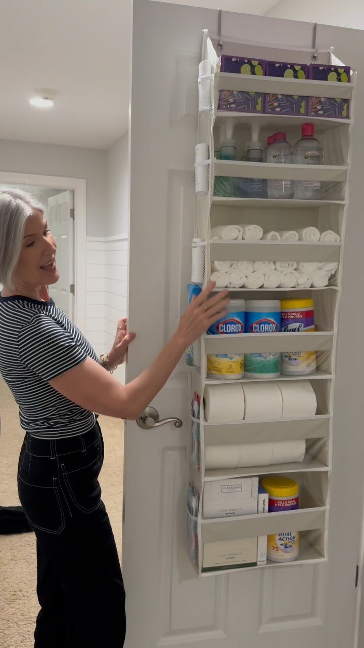 11 No Closet Room Ideas for Clothing Racks, Under-Bed Storage and More 3 A woman organizing household supplies in a white over-the-door hanging organizer.