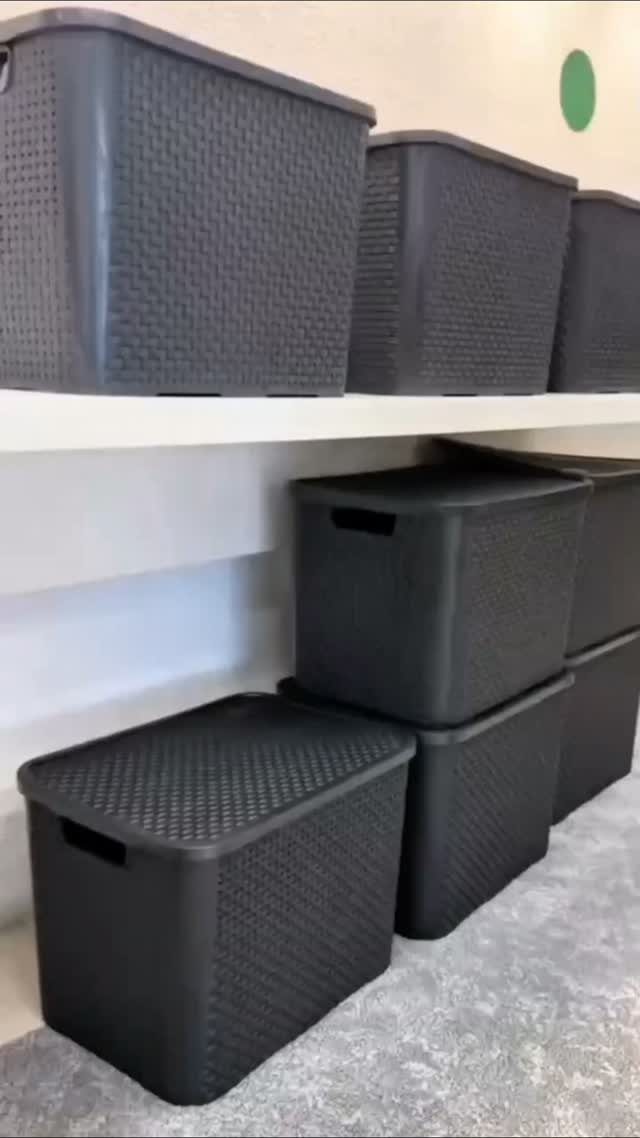 11 No Closet Room Ideas for Clothing Racks, Under-Bed Storage and More 6 Dark grey textured plastic storage bins stacked on a white shelf and floor.