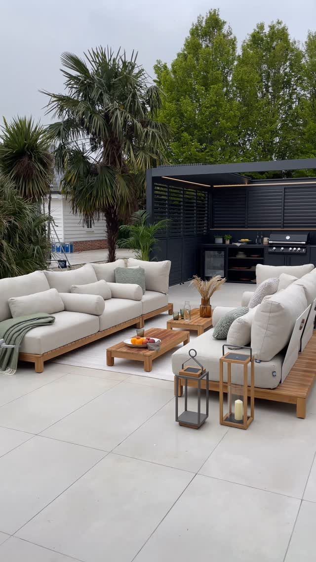 7 Outdoor Lounge Area Ideas for Entertaining and Relaxing 2 Wooden outdoor sofas with white cushions and pillows arranged on a tiled patio.
