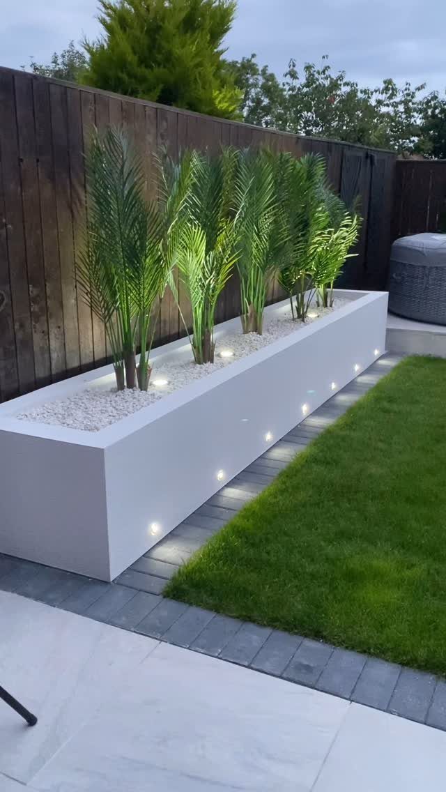 Outdoor Planter Boxes: 5 Ideas for Gardening, Balconies, and Modern Style 4 Long white rectangular planter box containing green palm plants and white gravel in a modern garden.