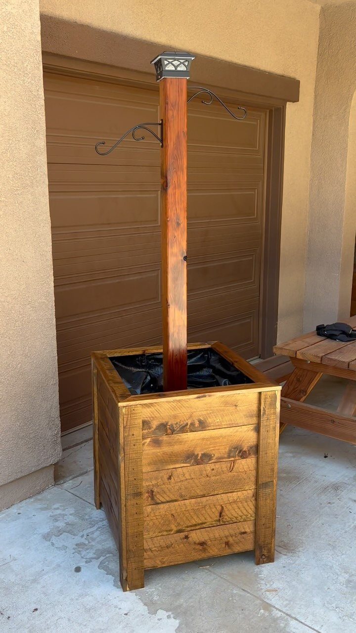 Outdoor Planter Boxes: 5 Ideas for Gardening, Balconies, and Modern Style 2 A large rectangular wooden planter box with a tall central post on a concrete patio.