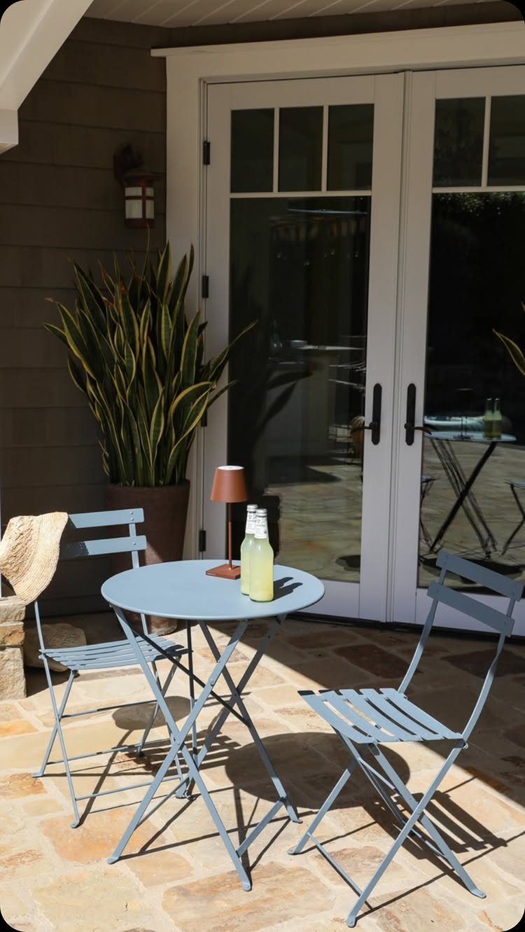 Patio Dining Table and 7 Outdoor Eating Area Ideas 2026 4 A light blue metal bistro set with a round table and two chairs on a patio.