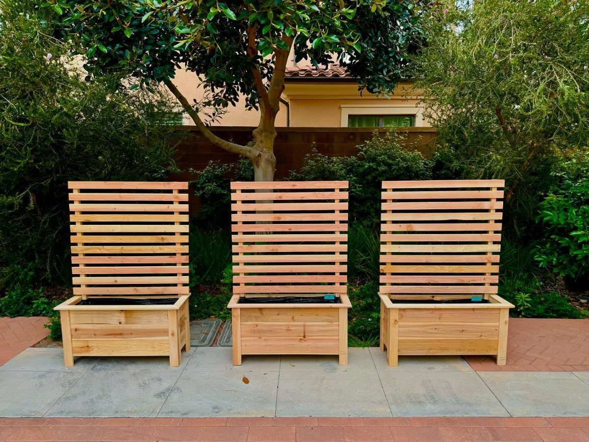 13 Planter Boxes Ideas for Your Porch, Deck and Garden 3 Three light wood planter boxes with tall slatted backrests arranged on a stone patio.