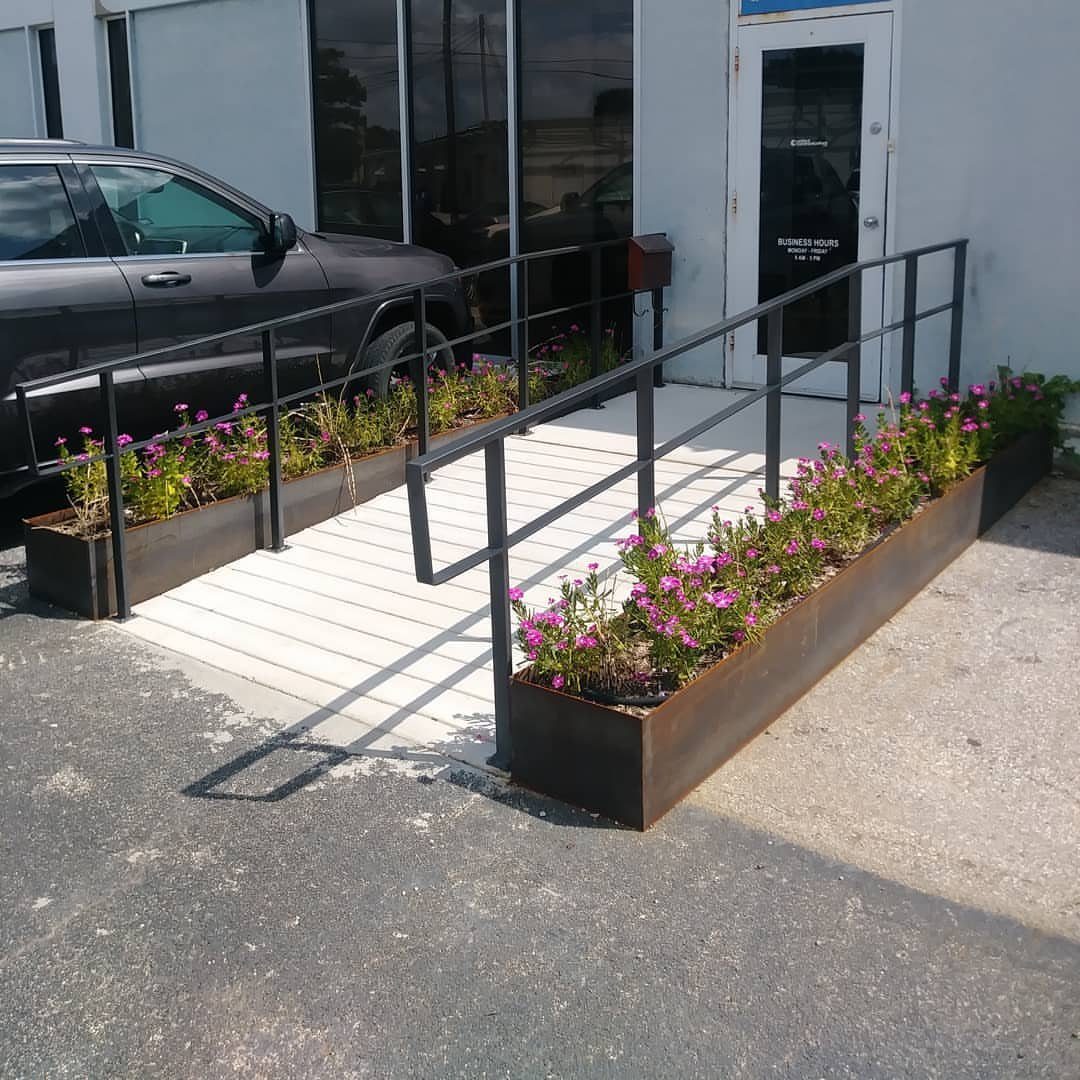 13 Planter Boxes Ideas for Your Porch, Deck and Garden 11 Long metal planter boxes with pink flowers lining a white wooden ramp entrance.