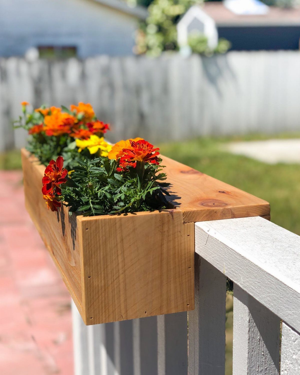 13 Planter Boxes Ideas for Your Porch, Deck and Garden 2 Wooden planter box with orange marigolds attached to a white deck railing outdoors.