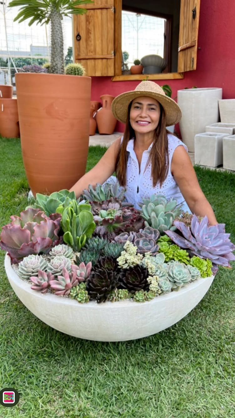 17 Pot Plants for Outdoor Spaces: Ideas That Thrive in Containers 14 A woman kneeling behind a large white bowl overflowing with diverse, colorful succulent plants outdoors.