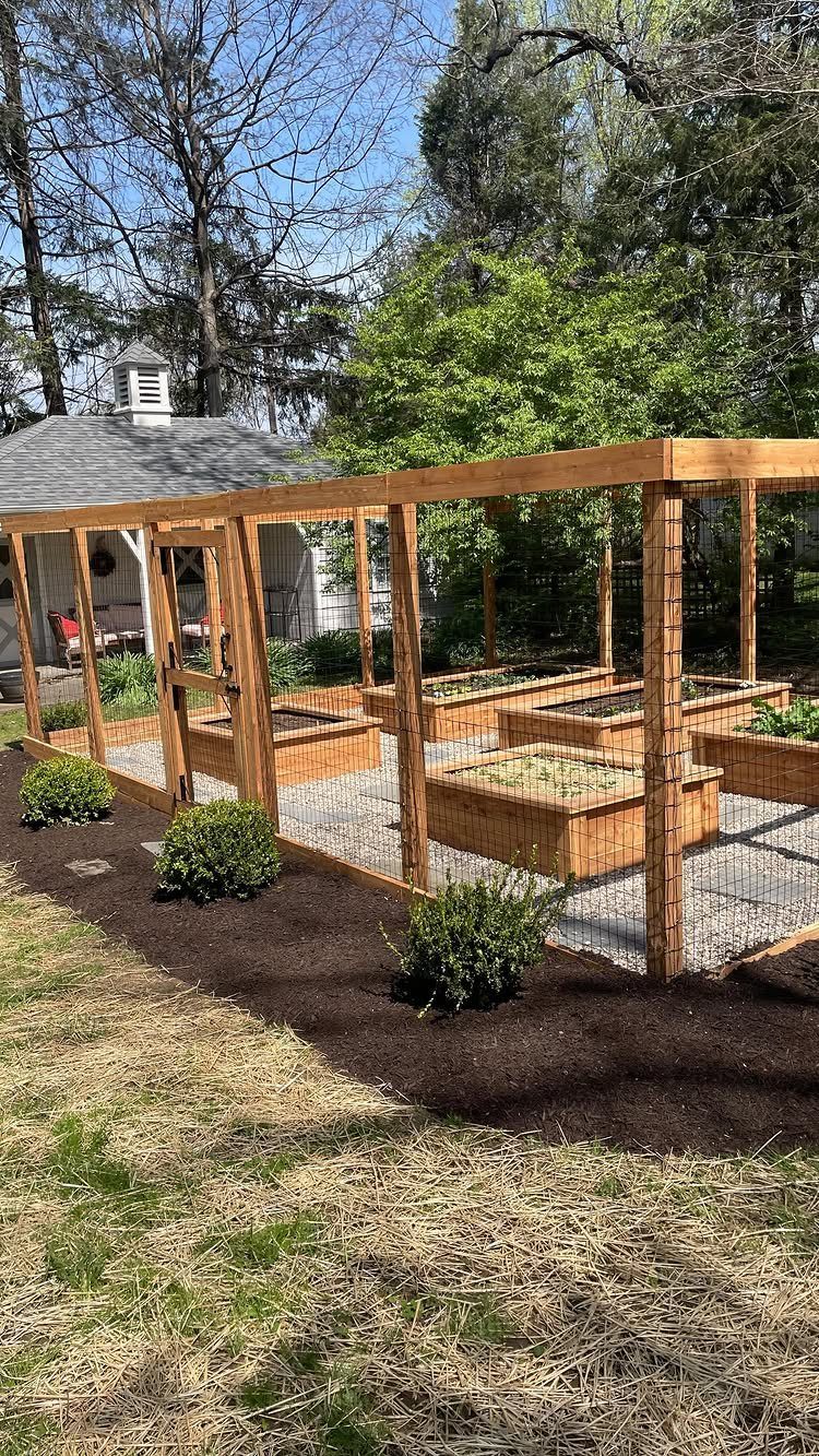 14 Raised Garden Bed Ideas for Cedar, Stone, Metal & More 1 Wooden raised garden beds arranged inside a large wooden mesh-sided garden structure.