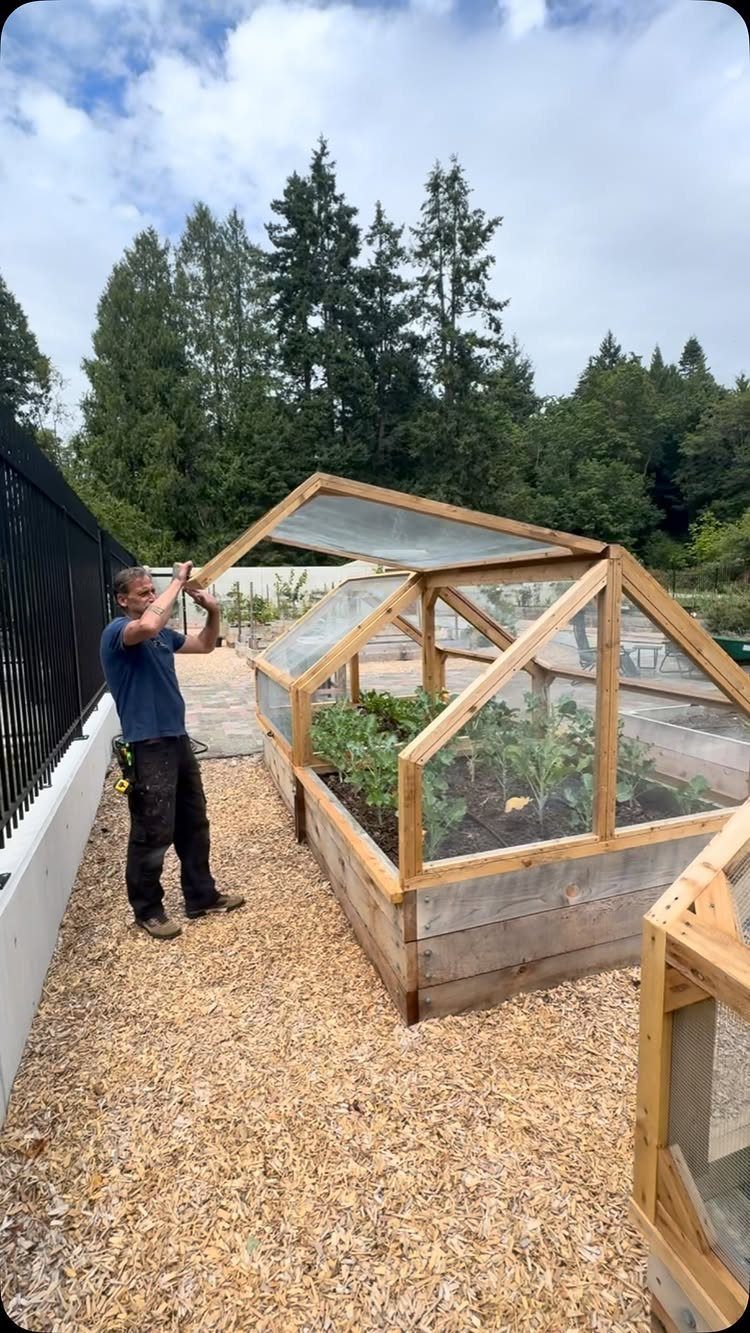 14 Raised Garden Bed Ideas for Cedar, Stone, Metal & More 12 A man assembling a wooden raised garden bed with a clear protective glass cover.