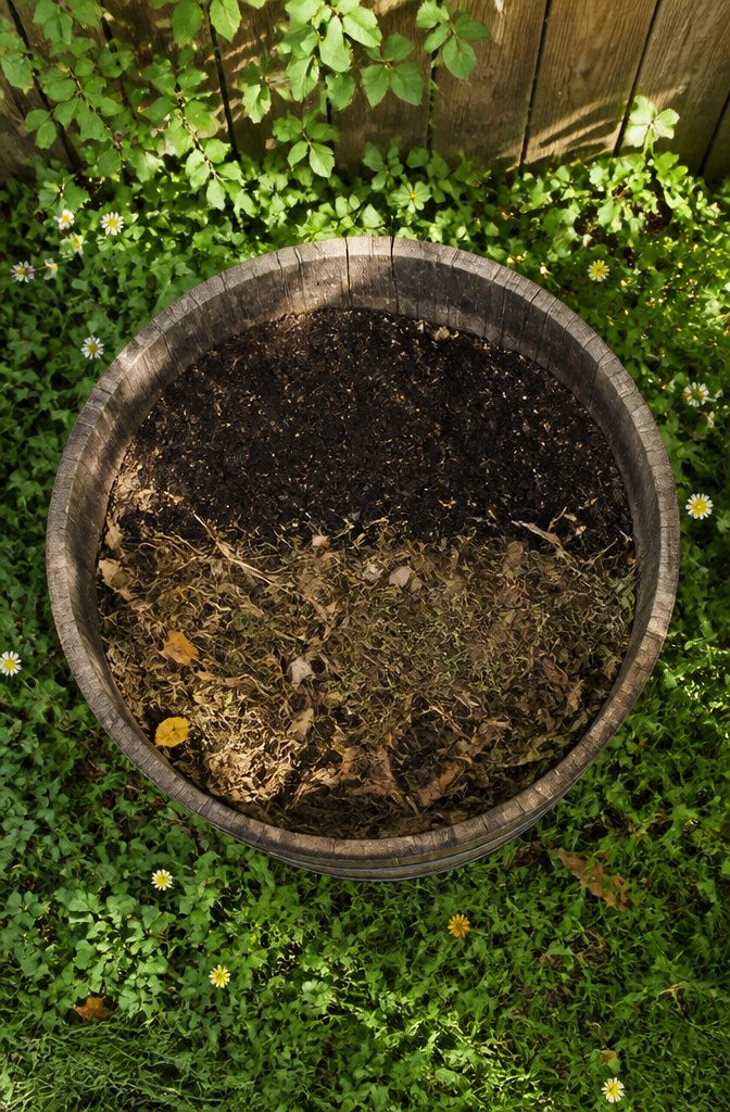 An oak barrel planter partially filled with leaves and twigs.