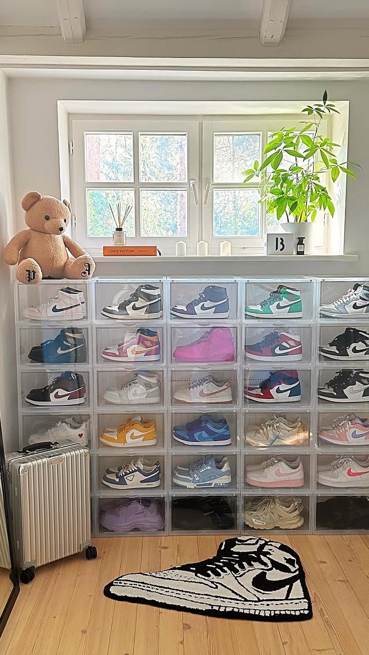 Clear plastic storage boxes filled with various colorful sneakers arranged in a large grid on a wooden floor.