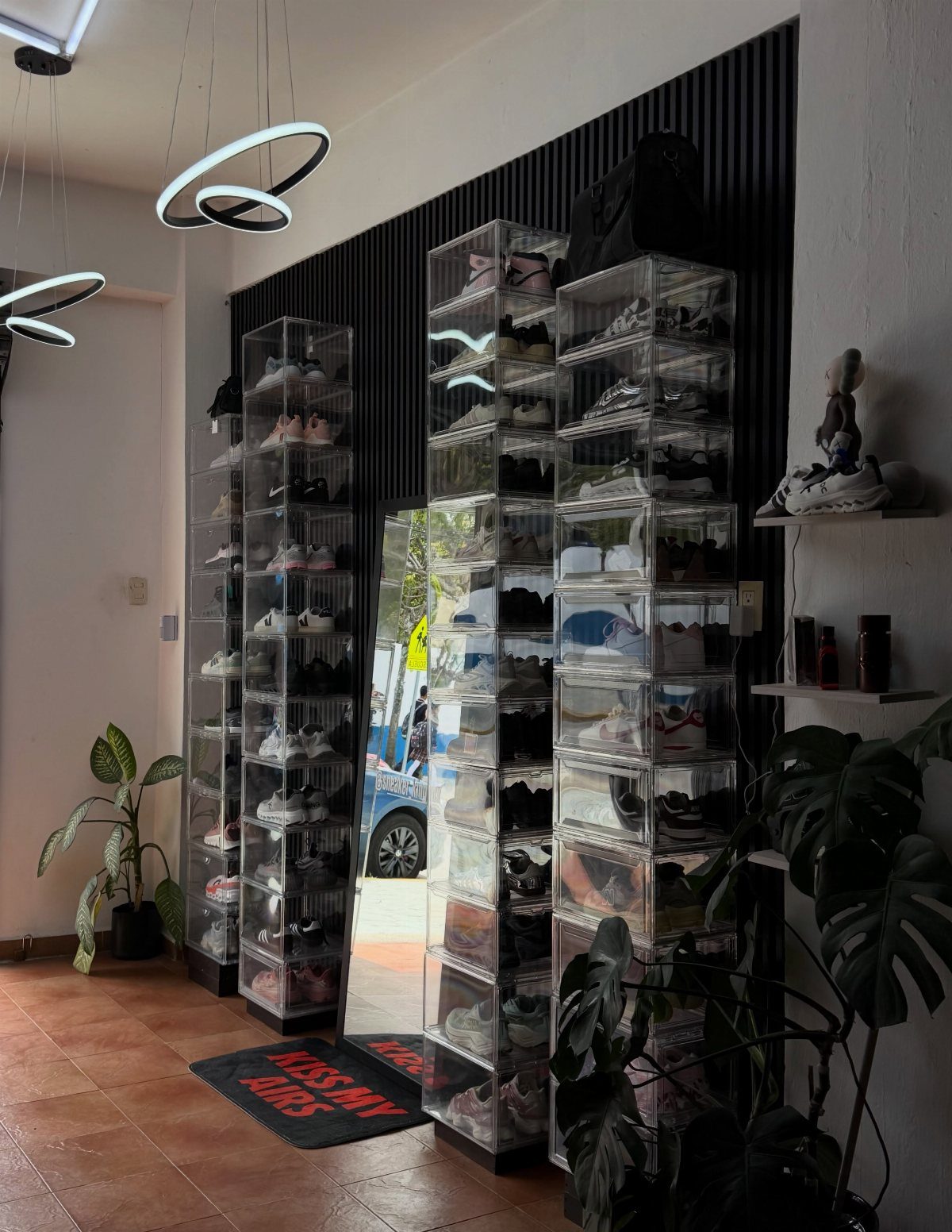 Clear acrylic sneaker display cases standing against a black slatted wall in a modern room.