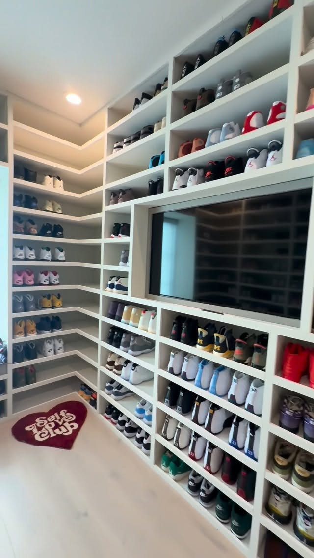 White built-in shelves filled with many colorful sneakers surrounding a television in a room.