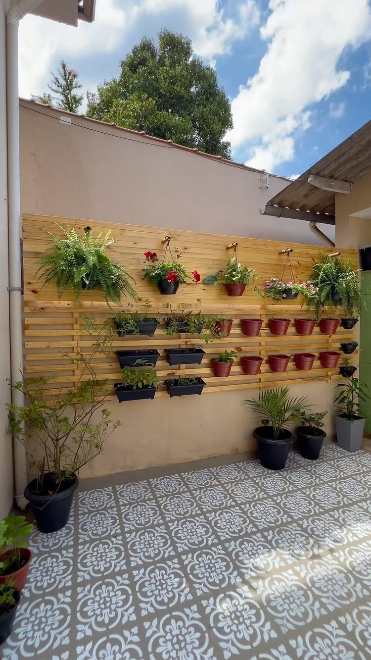 18 Small Backyard Garden Ideas for Compact Outdoor Style 2 Wooden slatted wall with various potted plants mounted on a beige exterior wall.